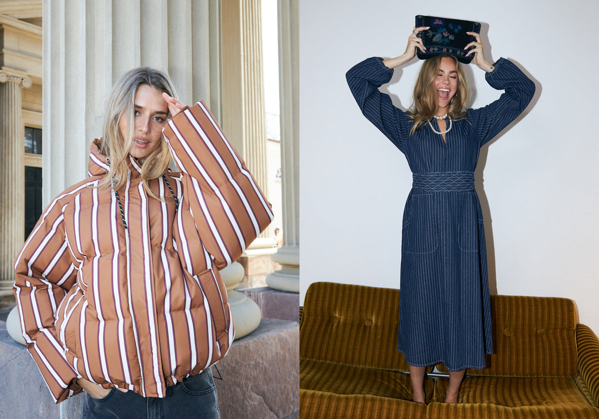 Zwei Frauen in unterschiedlichen Outfits. Eine trägt eine braun-rosa gestreifte Pufferjacke, während die andere ein dunkelblaues Midikleid mit Nadelstreifen trägt und eine bestickte Kosmetiktasche über dem Kopf hält.