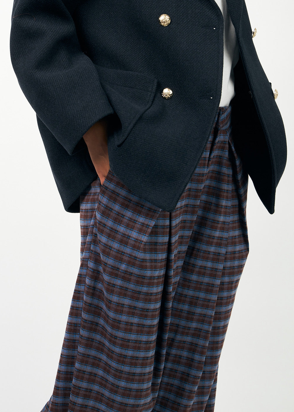 Weite karierte Hose mit Falten in Weinrot und Hellblau. Dazu trägt das Model eine Wolljacke im Sailor-Stil mit goldenen Knöpfen.
