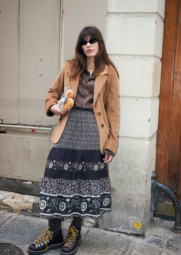 Frau in einem Kamelfarbenen Cord Blazer, einer braunen Bluse und einem langen braunen gemusterten Rock von Lollys Laundry auf einer Straße in der Stadt.